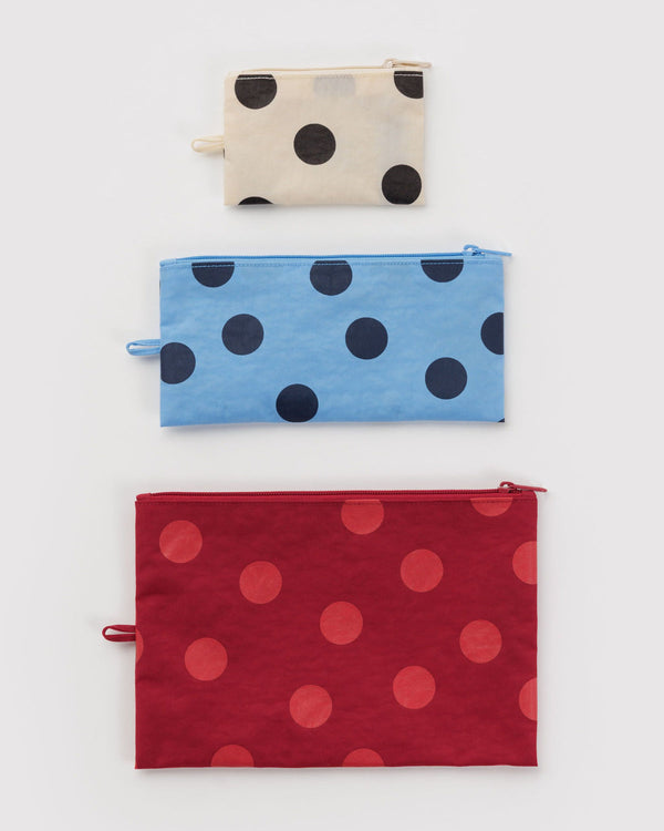 Three polka dot pouches in off-white & black, blue, and red on a white background