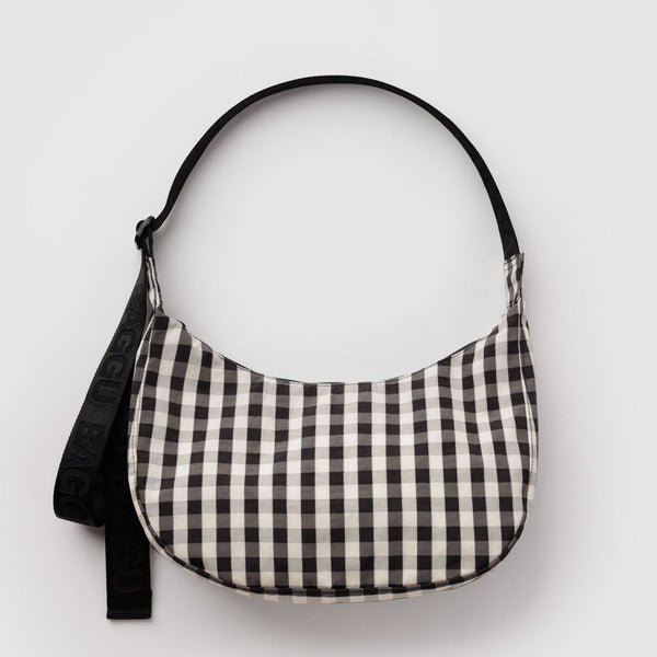 A black and off-white gingham crescent-shaped shoulder bag with a black strap, shown against a plain light gray background.