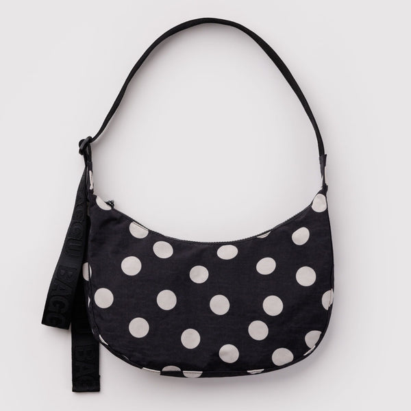A nylon crescent bag in black with off-white polka dots against a white backdrop.