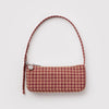 A small nylon pochette shoulder bag in a tan and red-brown houndstooth pattern with a silver metal smiley face charm against a white background.
