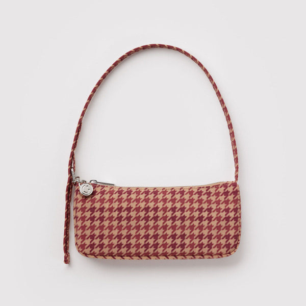 A small nylon pochette shoulder bag in a tan and red-brown houndstooth pattern with a silver metal smiley face charm against a white background.