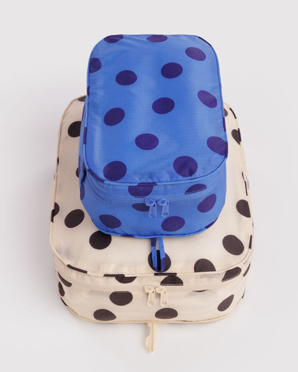 Blue polka dot small travel organizer on a larger cream and black polka dot travel organzer against a white background