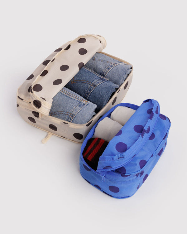 Polka dot travel organizers with denim and toiletries on a light gray background