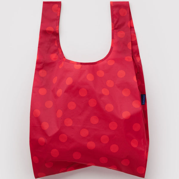 A nylon shopping bag in red with lighter red polka dots against a white backdrop.