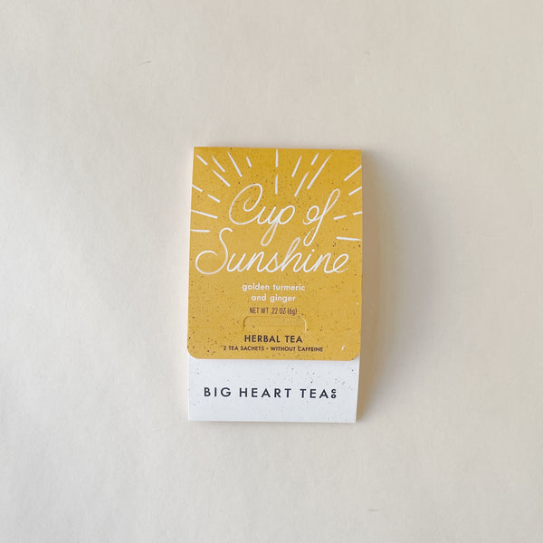 A packaged tea product labeled 'Cup of Sunshine' by Big Heart Tea, featuring a yellow and white color scheme with sunburst graphics.