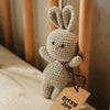 Crocheted rabbit rattle toy with a 'Bitsy Zoo' tag on a wooden surface
