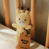 Crocheted giraffe rattle toy with a 'Bitsy Zoo' tag on a wooden surface