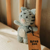 Crocheted blue and black cat rattle toy with a 'Bitsy Zoo' tag on a wooden surface
