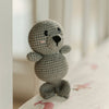 Crocheted seal rattle toy on a soft surface with a blurred background