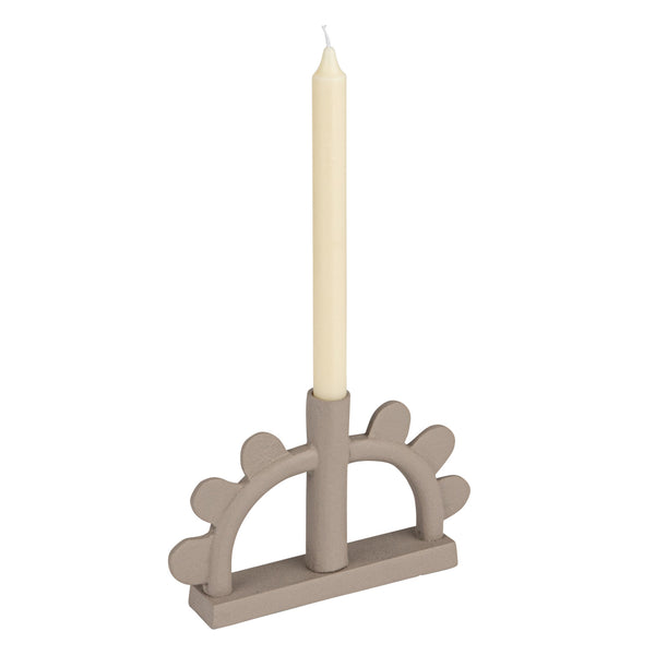 A single cream taper candle displayed in a taupe-colored decorative holder with a scalloped arch design, set against a plain white background.