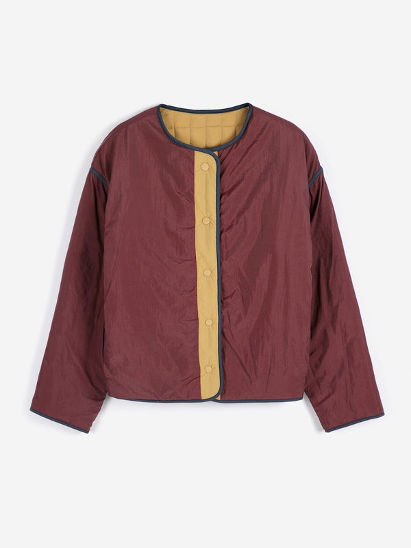 A dark red and mustard tan colorblock jacket with the puffer reverse as liner against a white background.