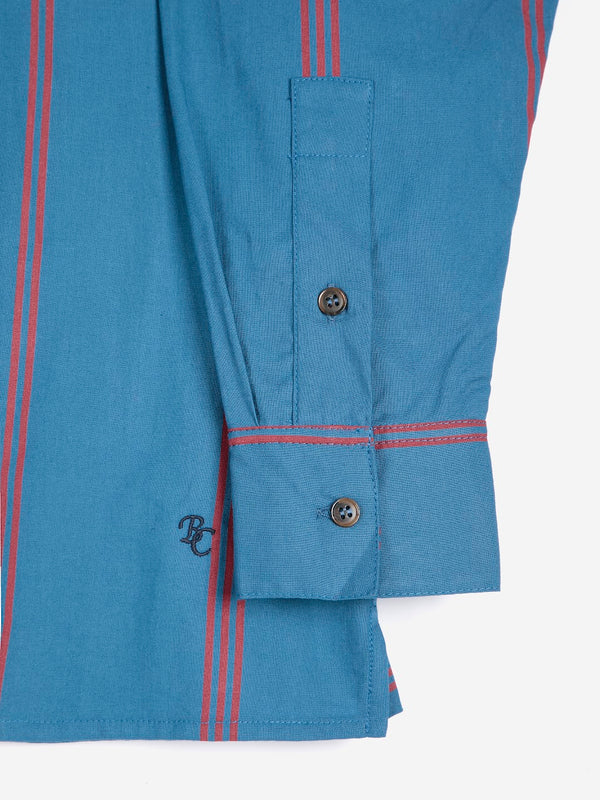 A close-up detail of the sleeve and embroidered 'BC' hem monogram on a bold blue and red triple stripe poplin collared shirt against a white background.