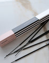 Incense sticks with pink, black, and white packaging on a marble surface