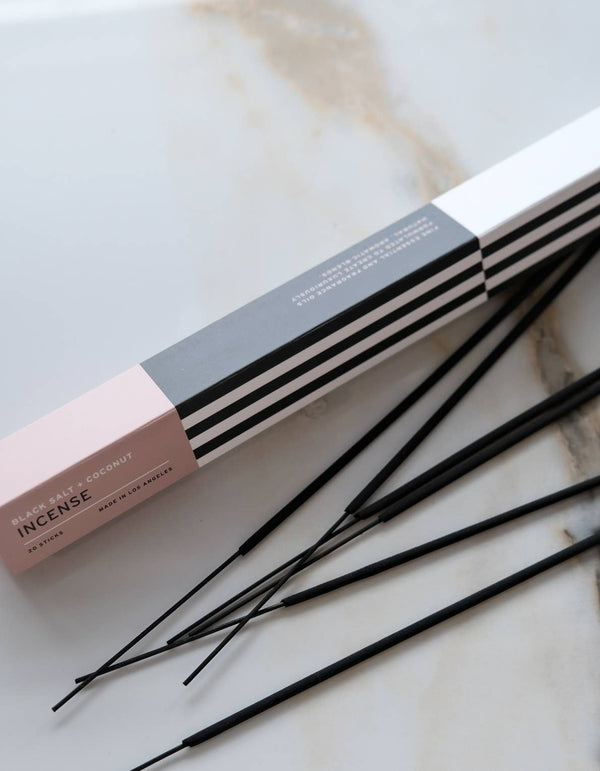 Incense sticks with pink, black, and white packaging on a marble surface