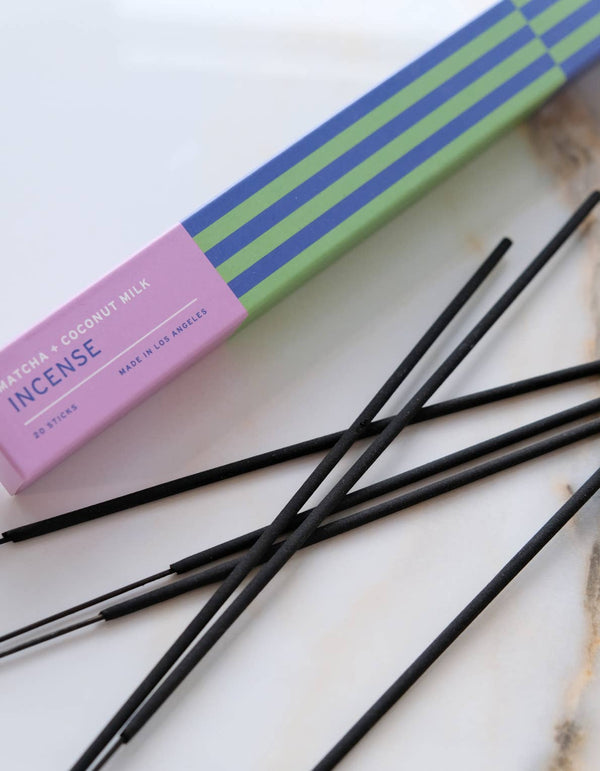 Incense sticks with a box labeled 'Matcha + Coconut Milk' on a marble surface