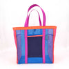 A bold blue mesh tote bag with pink and orange details. There is a navy front pocket on the bag. 