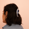 Person with a decorative fish hair clip on a pink background