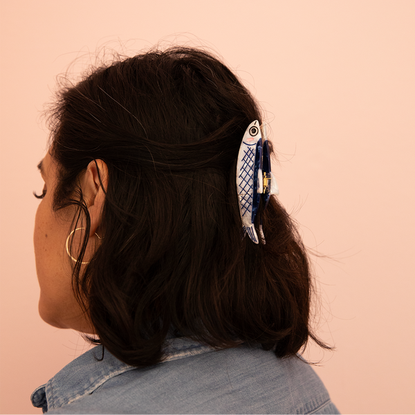 Person with a decorative fish hair clip on a pink background