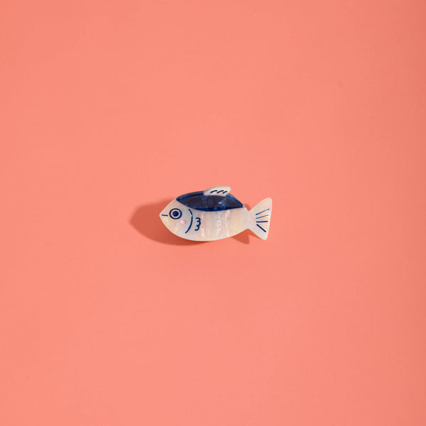 Small navy and iridescent white dashi fish hair claw on a pink background