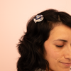 Person with a hair clip featuring a fish design on a pink background
