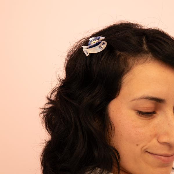 Person with a hair clip featuring a fish design on a pink background