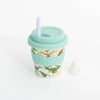 A reusable sippy cup in a green dino print with green silicone wavy grip, lid, and straw against a white background.