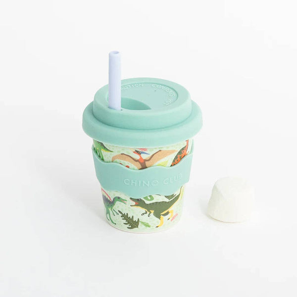 A reusable sippy cup in a green dino print with green silicone wavy grip, lid, and straw against a white background.