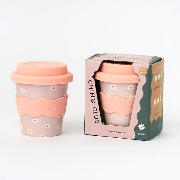 Reusable cup with pink lid and sleeve, featuring a daisy design, and packaging on a white background.