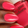 Hand with bright pink nails holding a bottle of 'cirque colors' nail polish.