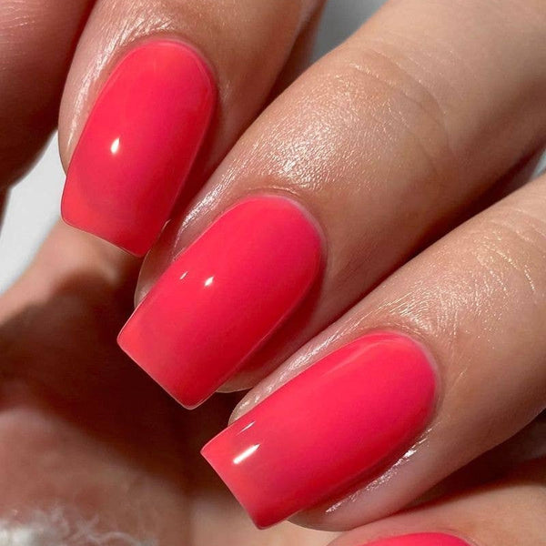 Close-up of a hand with bright pink nail polish on a neutral background