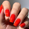 Hand with bright red nail polish on a neutral background