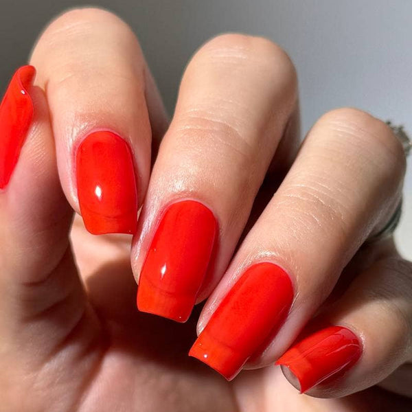 Hand with bright red nail polish on a neutral background