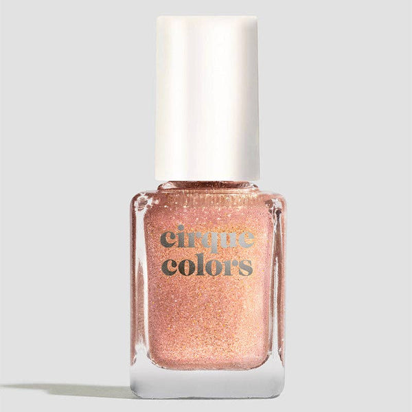 A bottle of cinque colors glitter nail polish in a shimmering peachy rose gold shade, featuring a white cap and gold lettering on a light gray background.