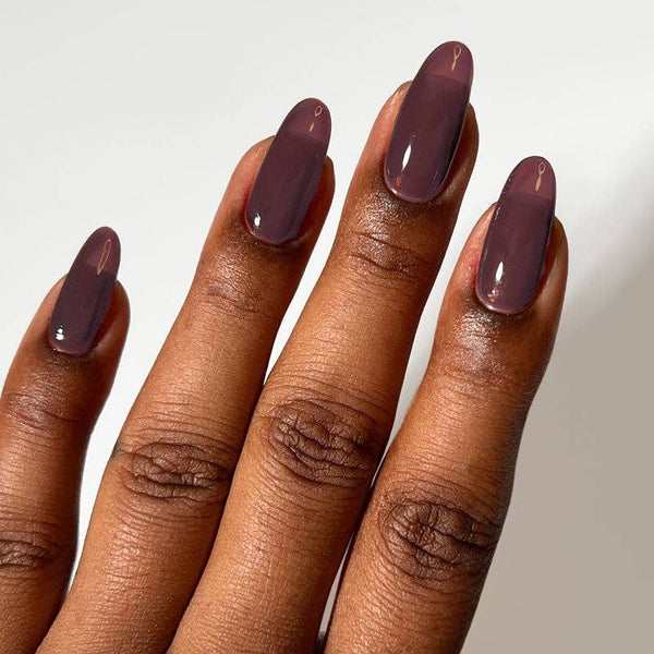 A close-up of a hand with long, almond-shaped nails painted in a glossy, muted mahogany shade against a plain light background.