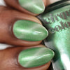 Close-up of a hand with green nail polish holding a bottle of Cirque Colors nail polish.