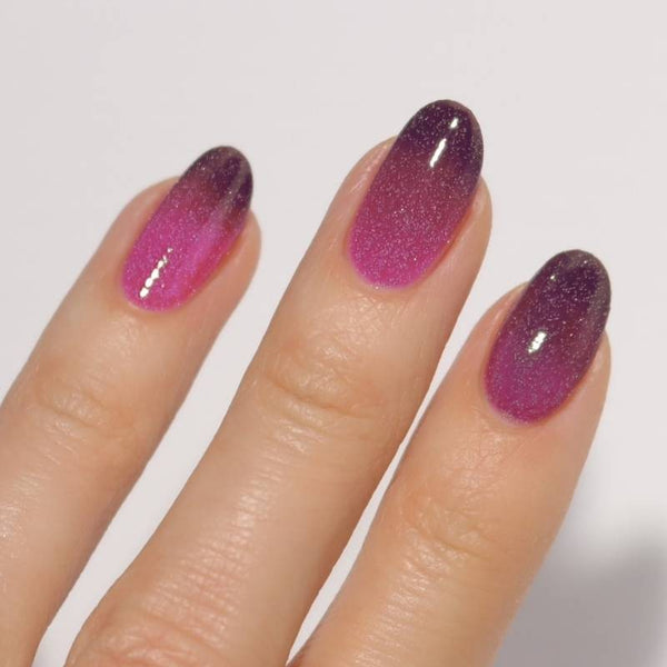 Nails with a gradient from purple to pink on a plain background