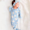 Newborn baby in a blue floral outfit with a matching headband on a white background