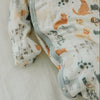 Baby swaddle with animal pattern showing detail of fold-over mitts on a light background