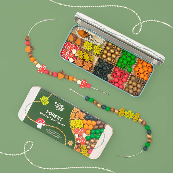 Forest-themed bracelet making kit with beads and tools on a green background