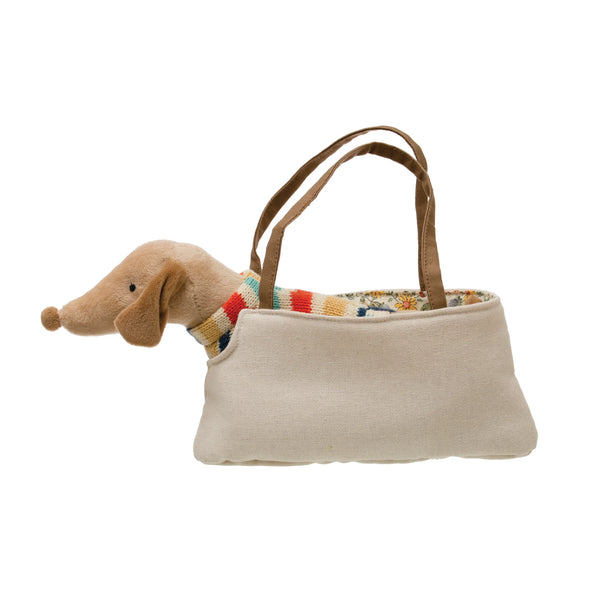 A beige canvas mini purse bag with brown handles, featuring a plush dachshund toy tucked inside the bag and a colorful patterned fabric lining visible at the opening.
