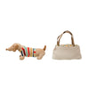 Stuffed dog toy with a colorful sweater next to a small handbag on a white background