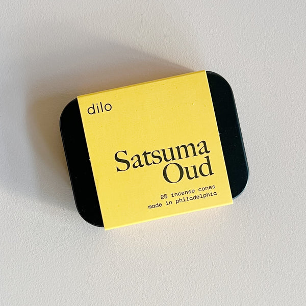 A black tin of 'dilo' Satsuma Oud incense cones with bright yellow label on a neutral background.