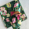 Floral-patterned napkin with a wooden ring on a white background