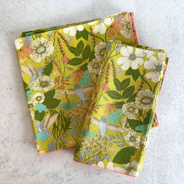 Bold yellow and green hummingbird botanical print cotton napkins on a neutral background.