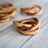 Wooden interlocking napkin rings on a light wooden surface
