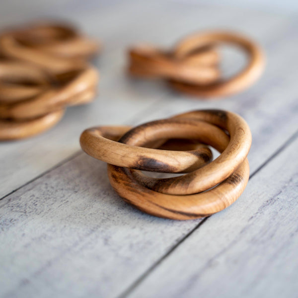 Wooden interlocking napkin rings on a light wooden surface