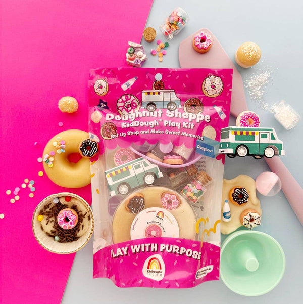 Doughnut-themed play dough kit packaging on a pink and gray background with donut decorations.