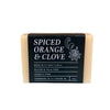 A bar of pale orange soap with a black brand label photographed on a white backdrop.