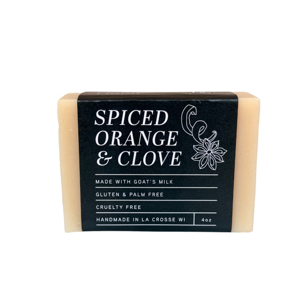 A bar of pale orange soap with a black brand label photographed on a white backdrop.