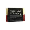 A bar of peppermint soap in cream and dark red with a black brand label photographed on a white backdrop.